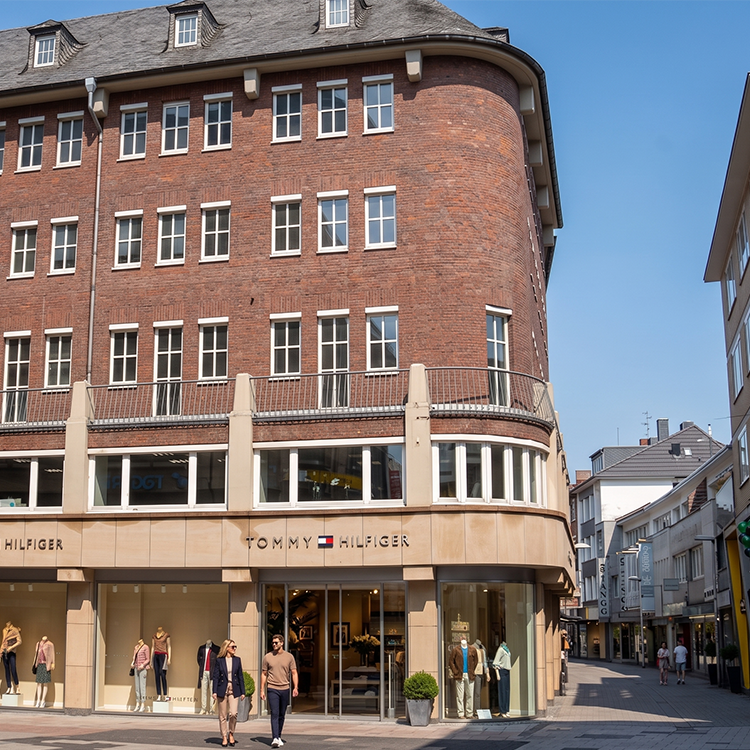 Zu sehen ist eine Mixed-use Immobilie mit einem Tommy Hilfiger Flagshipstore und darüber vier Etagen mit Wohnungen in der Stadt Aachen (NRW); ein Referenzobjekt der Firma unimo real estate concepts