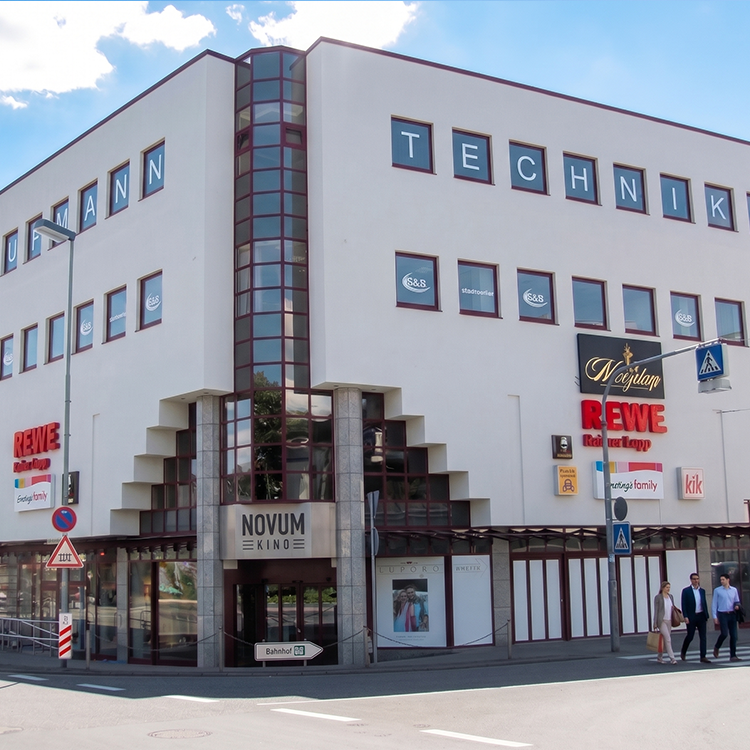 Zu sehen ist ein Nahversorgungszentrum mit einem Rewe Markt, einem Ernsting‘s Family-Geschäft, einem kik-Laden sowie das Novum-Kino in der Stadt Büdingen (Hessen); ein Referenzobjekt der Firma unimo real estate concepts
