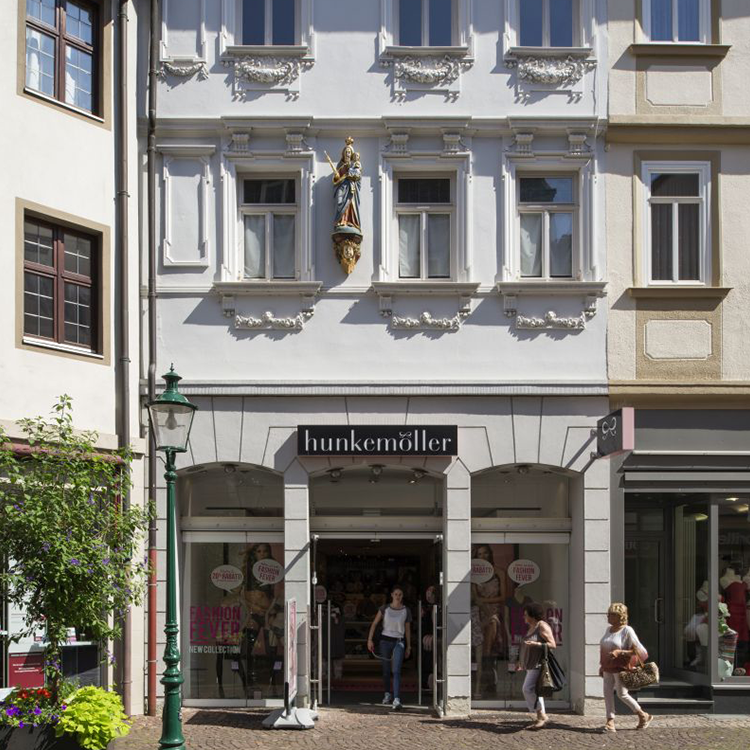 Zu sehen ist eine Mixed-use Immobilie in der Stadt Fulda (Hessen) mit einem Bekleidungsgeschäft sowie darüberliegenden Wohnungen; ein Referenzobjekt der Firma unimo real estate concepts