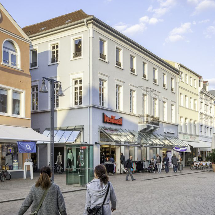 Zu sehen ist eine Mixed-use Immobilie in der Fußgängerzone in der Stadt Speyer (RP) mit einer New-Yorker-Filiale im Erdgeschoss sowie zwei Etagen mit Wohnungen; ein Referenzobjekt der Firma unimo real estate concepts